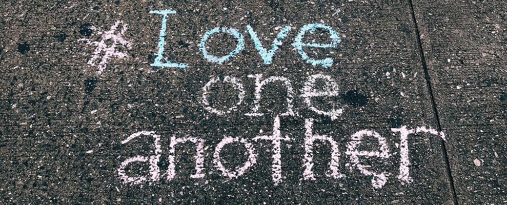 This is a picture of the words "Love one another" written with sidewalk chalk.